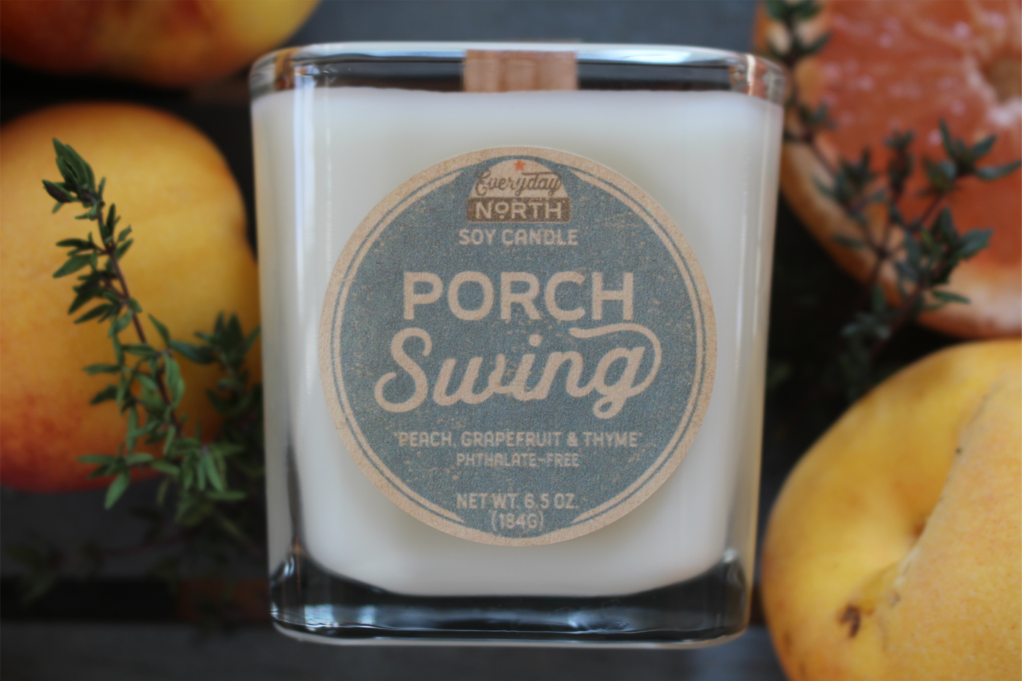 Everyday North Wood Wick Soy Candle. Porch Swing. Peach, Grapefruit and Thyme. Phthalate Free. 6.5 oz. 184 grams. Decor Surrounding Undyed Soy Wax Candle in Cube Glass Jar.
