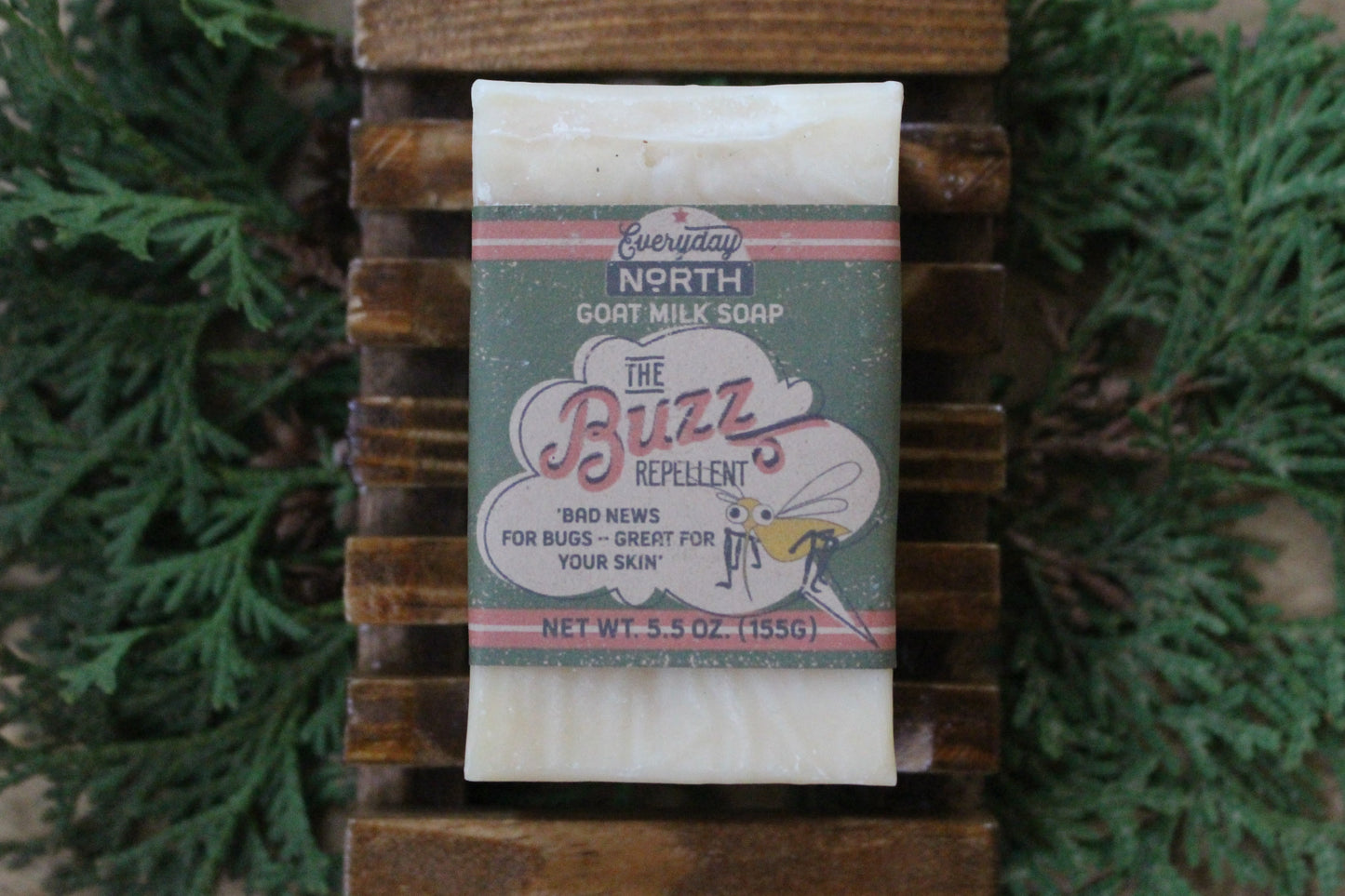 Undyed Soap Bar on Soap Dish. Wrapped in Kraft Label. Everyday North Goat Milk Soap. The Buzz. Bad News For Bugs- Great For Your Skin. 5.5 oz. 155 grams. Surrounded by decor.