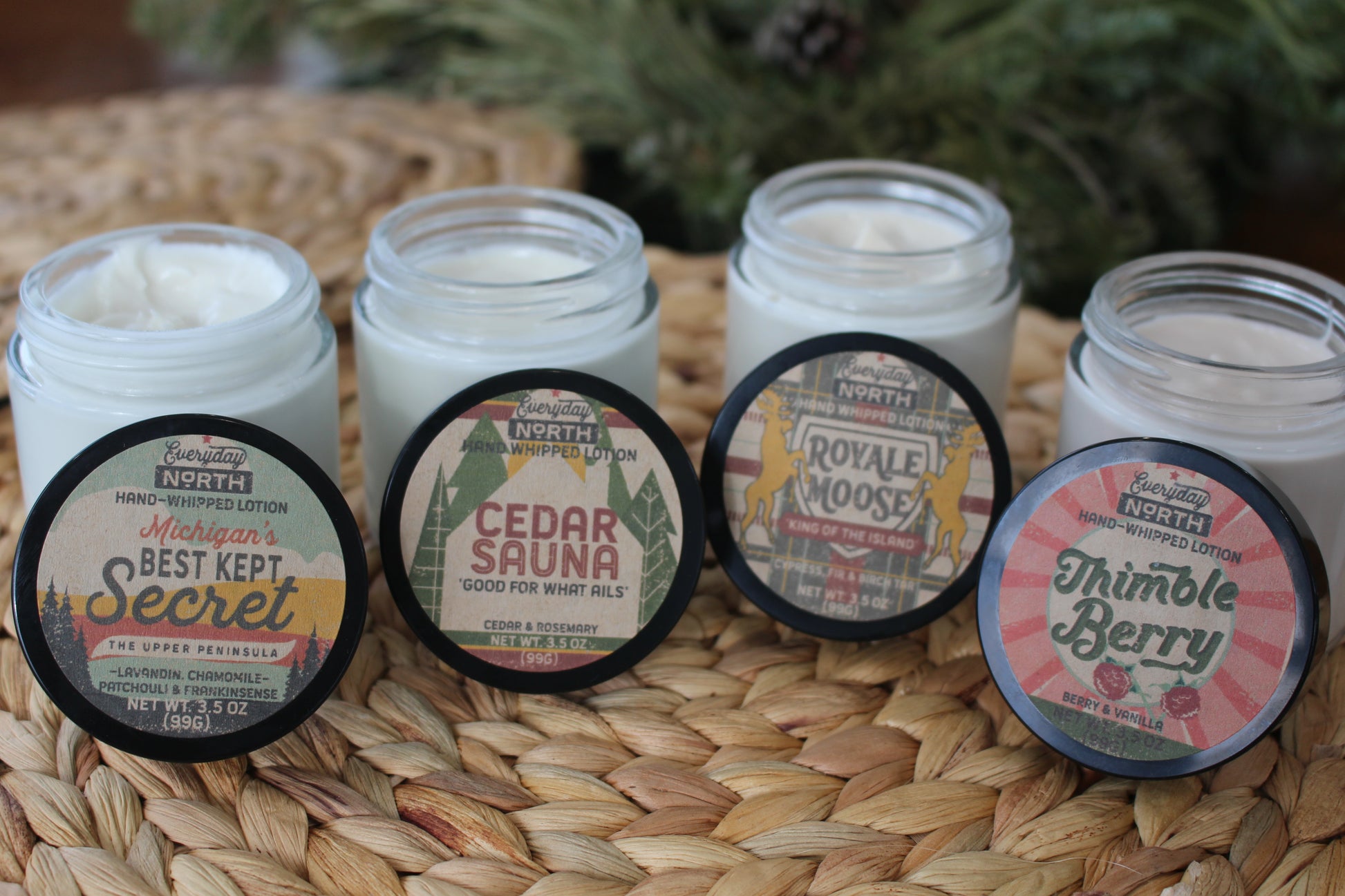 Four glass jars filled with white, whipped lotion. Black covers off, leaning against each jar showing the variety. Best Kept Secret, Cedar Sauna, Royale Moose and Thimbleberry.