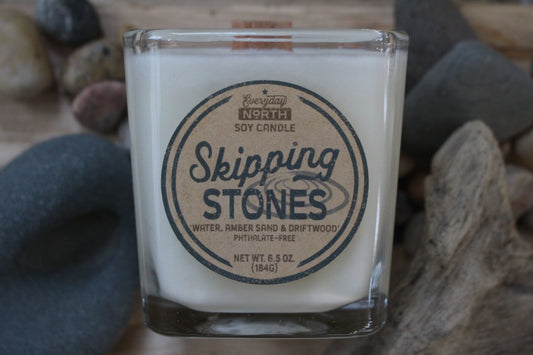 Everyday North Wood Wick Soy Candle. Skipping Stones. Water, Amber Sand and Driftwood. Phthalate Free. 6.5 oz. 184 grams. Decor Surrounding Undyed Soy Wax Candle in Cube Glass Jar.