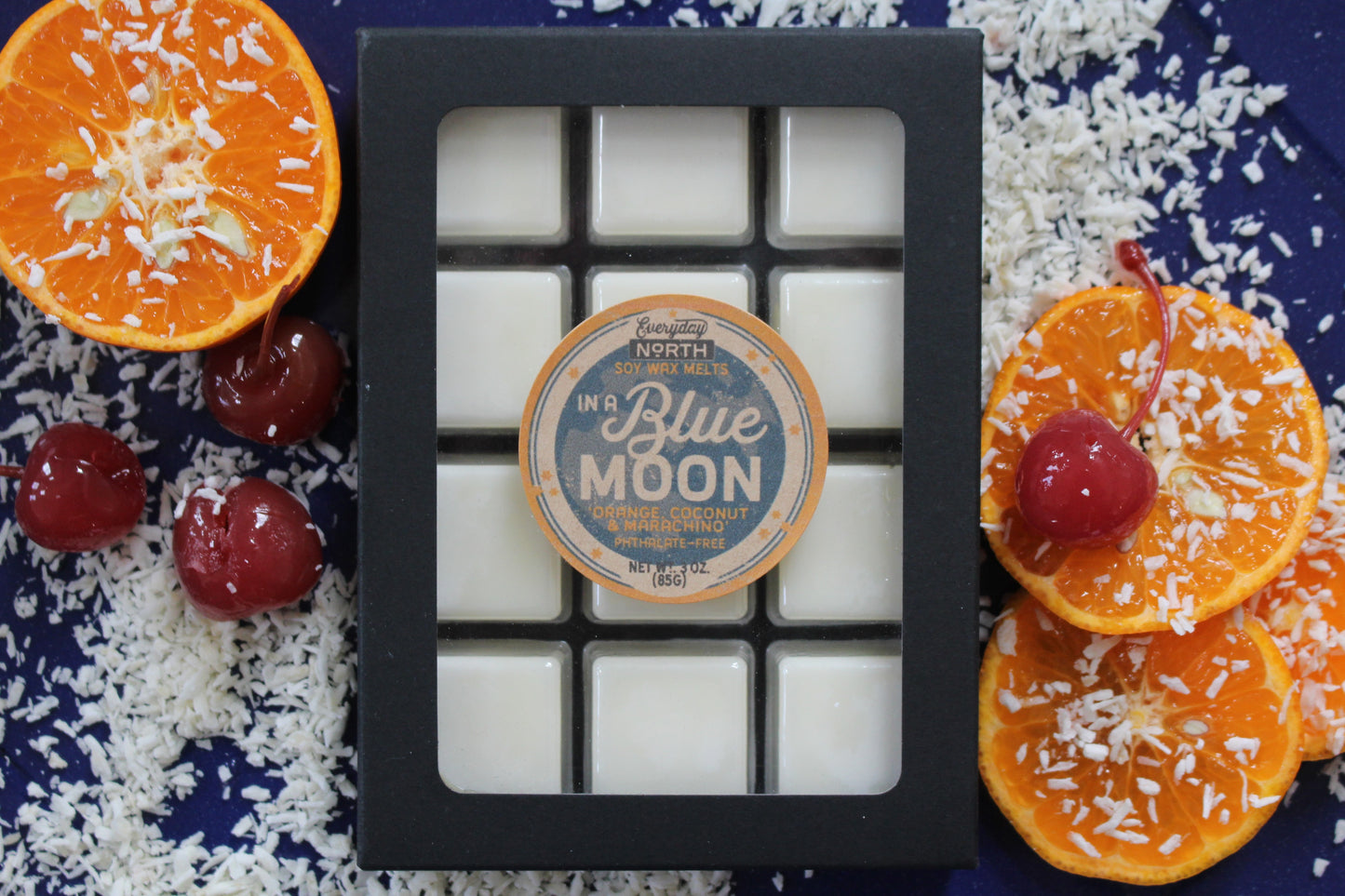 Everyday North Soy Wax Melts. In a Blue Moon. Orance, Coconut and Maraschino. Phthalate Free. 3 oz. 80 grams. Decor Surrounding 12 Tray Wax Melt Undyed Black Box.